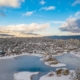 Aerial view of Big Bear Lake and town in California with the lake frozen on a sunny blue sky day in the Winter with pine trees below.