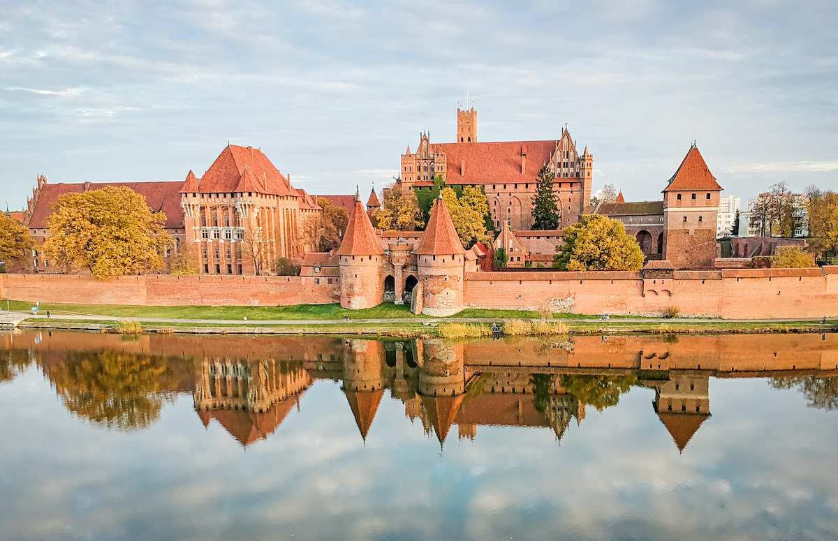 Malbork castle autumn panorama with reflection, at sunset